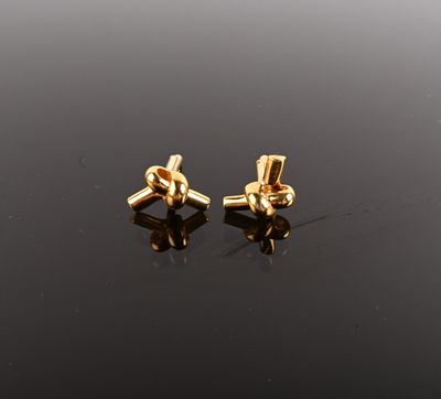 a pair of gold earrings on a black surface