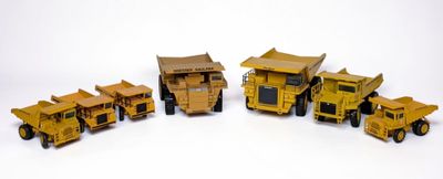cinq camions miniatures alignés les uns à côté des autres sur une surface blanche