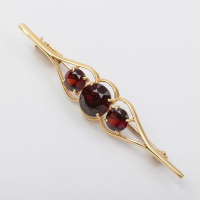 a close up of a gold brooch with three garnets on it