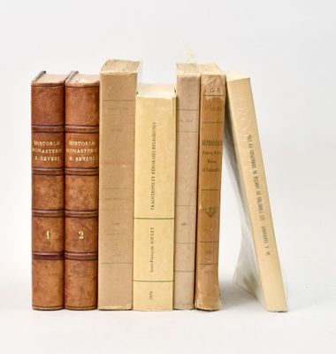 plusieurs vieux livres sont empilés sur une surface blanche