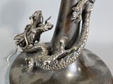 a silver vase with a dragon on it on a table