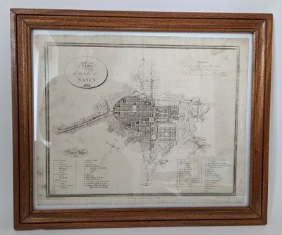 une vieille carte d'une ville, encadrée dans un cadre en bois, accrochée au mur