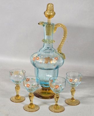 a blue glass decanter with a gold handle and four glasses