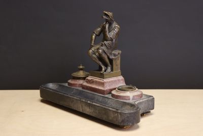 une statue en bronze représentant un homme assis sur une valise