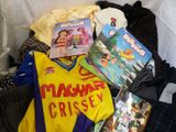 a pile of children ' s clothing and books on a bed