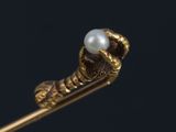 a close up of a piece of gold with a pearl in it