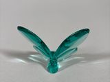 a small green glass butterfly on a white surface