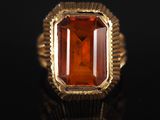 un gros plan d'une bague ornée d'une pierre orange sur un fond noir