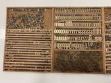 many different types of metal letters and numbers in a wooden box