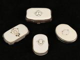 four white porcelain pill cases sitting on top of a black surface