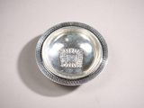 un petit plat en argent avec un couvercle en argent posé sur une table