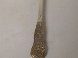 a silver spoon with a spoon handle on a white surface