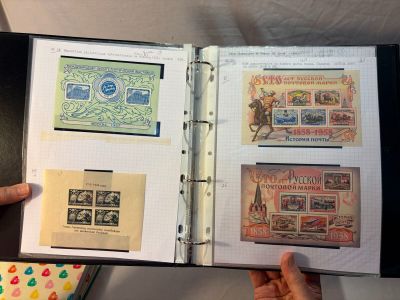 une personne tenant un livre ouvert sur lequel figurent des timbres