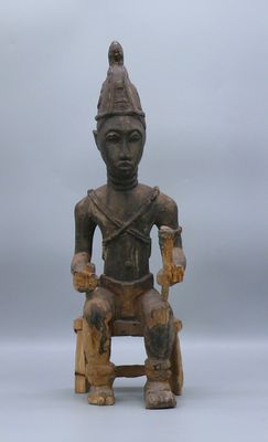 une vieille statue en bois représentant un homme assis sur une chaise