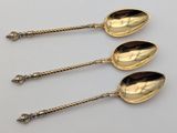 three silver spoons sitting on top of each other on a table