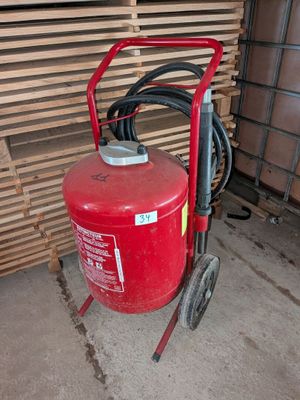 un extincteur rouge posé à côté d'un tas de bois