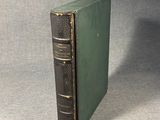 a green book sitting on top of a table next to a gray wall