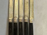four knives are lined up on a table with a white cloth