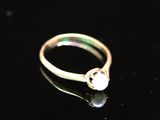 un gros plan d'une bague en or sertie d'une perle sur un fond noir