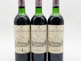 trois bouteilles de vin rouge posées l'une à côté de l'autre sur une surface blanche