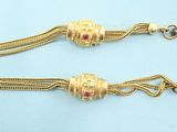 a close up of two gold chains with red stones on them