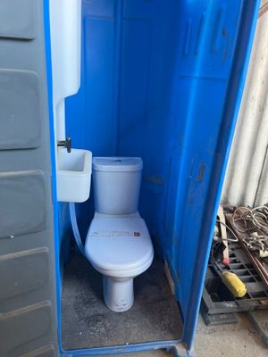des toilettes situées dans une cabine de toilettes portables bleue équipée d'un lavabo