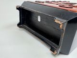 a black box with a brown handle sitting on a white surface