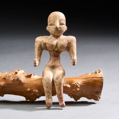 figurine représentant une femme assise sur un tronc d'arbre