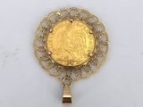 a gold coin pendant with a bell hanging from it ' s center