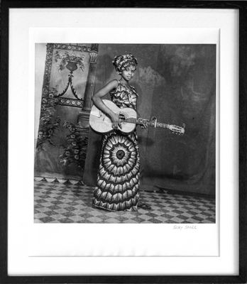 an old black and white photo of a woman with a guitar
