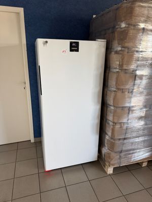 un réfrigérateur au milieu d'une pièce, à côté d'une pile de palettes