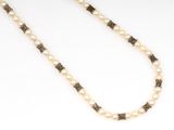 a close up of a necklace with pearls on a white surface