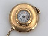 an image of a gold pocket watch with a chain on a white surface