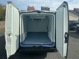 une camionnette blanche dont les portes sont ouvertes, garée sur un parking