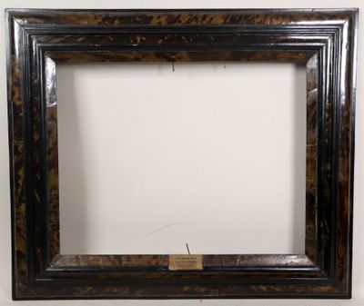an old picture frame with a tag on it sitting on a wall