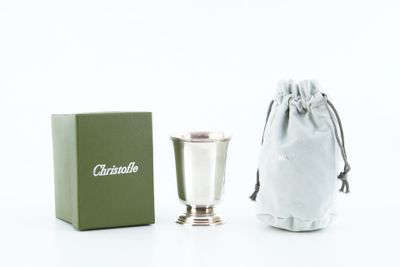 a silver cup next to a green box on a white surface