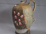 a brown vase with flowers on it sitting on a table