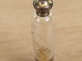 a small glass bottle with a silver lid on a wooden table