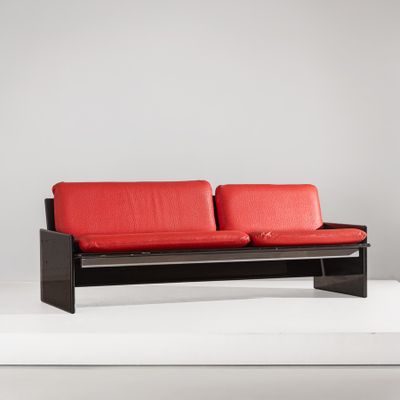 une image représentant un canapé rouge posé sur une surface blanche