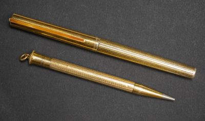 deux stylos dorés posés l'un à côté de l'autre sur une surface noire