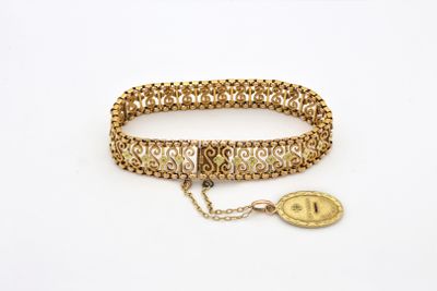 Gros plan sur un bracelet en or orné d'une pièce de monnaie