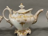 two white and gold teapots sitting next to each other