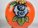 an orange vase with a rose painted on it