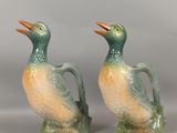 une paire de figurines de canards verts et orange, assises l'une sur l'autre