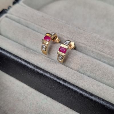 une paire de boucles d'oreilles en rubis et diamants, dans un écrin posé sur une table