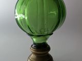 un vase en verre vert posé sur une table, avec un socle en bois