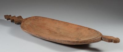 un vieux bol en bois muni d'une poignée, posé sur une surface blanche