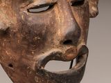 a close up of a wooden mask on a metal stand