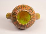 a yellow and green vase sitting on a white surface