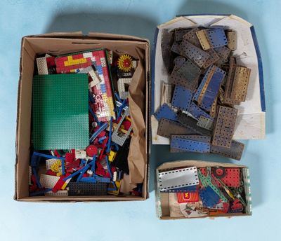 une boîte remplie de Lego et d'autres jouets posée sur une surface bleue